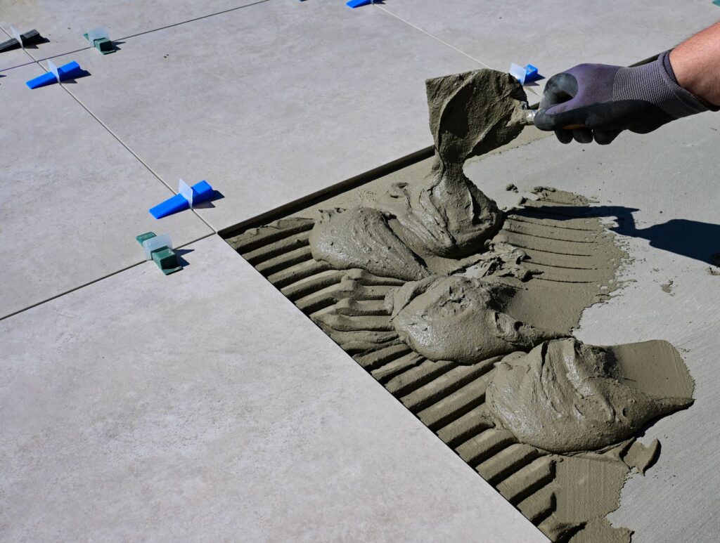 Professional tiler's equipment laid out on a job site, tile saw, trowels, levels, and grout tools