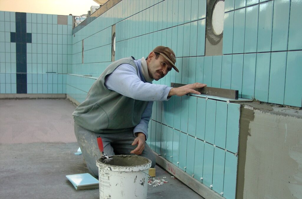 Professional tiler installing large format tiles in a modern US bathroom renovation