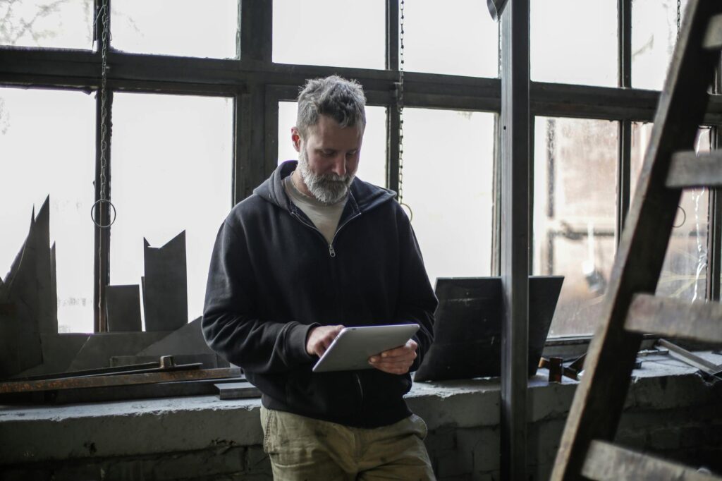 A handyman checking their phone app between jobs, tools loaded in a truck bed in the background