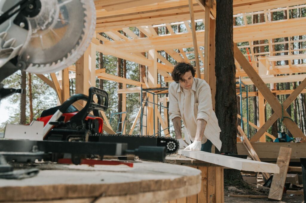 Carpenter contractor reviewing a job quote on a smartphone at a US job site, professional workwear and tools visible