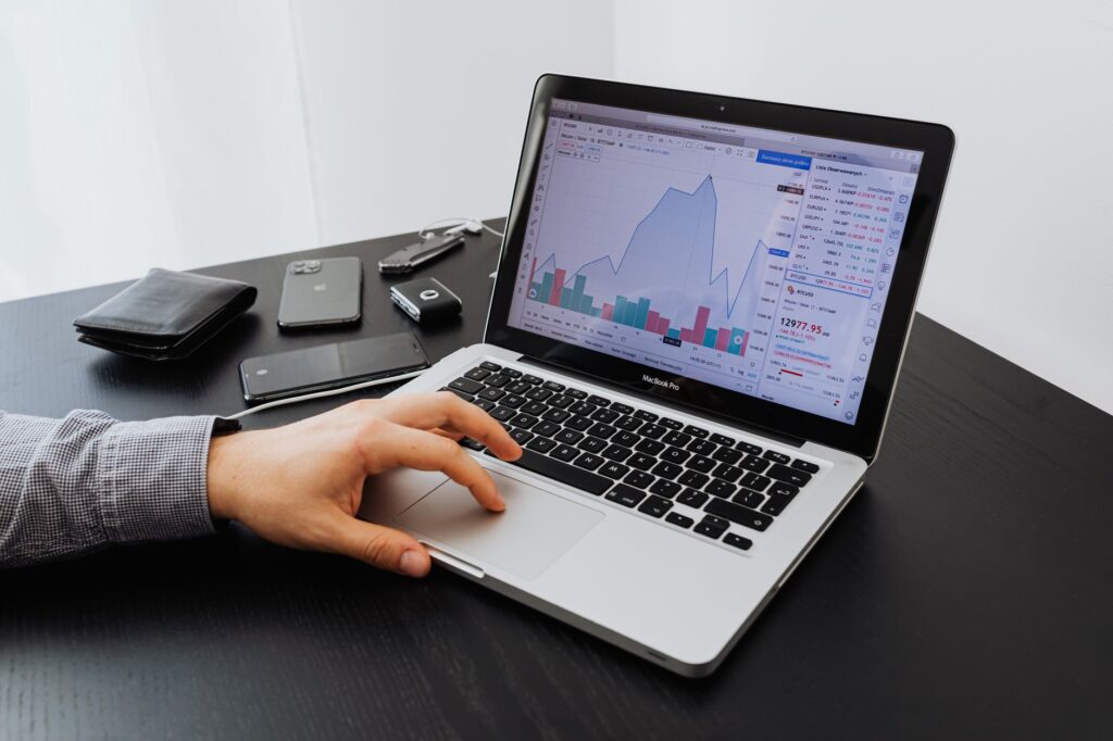 UK trades business owner reviewing marketing costs on a laptop, notepad with budget figures beside it